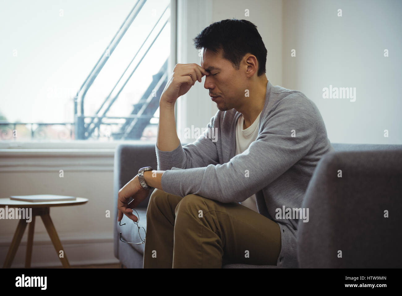 Tendu man sitting on sofa in living room Banque D'Images