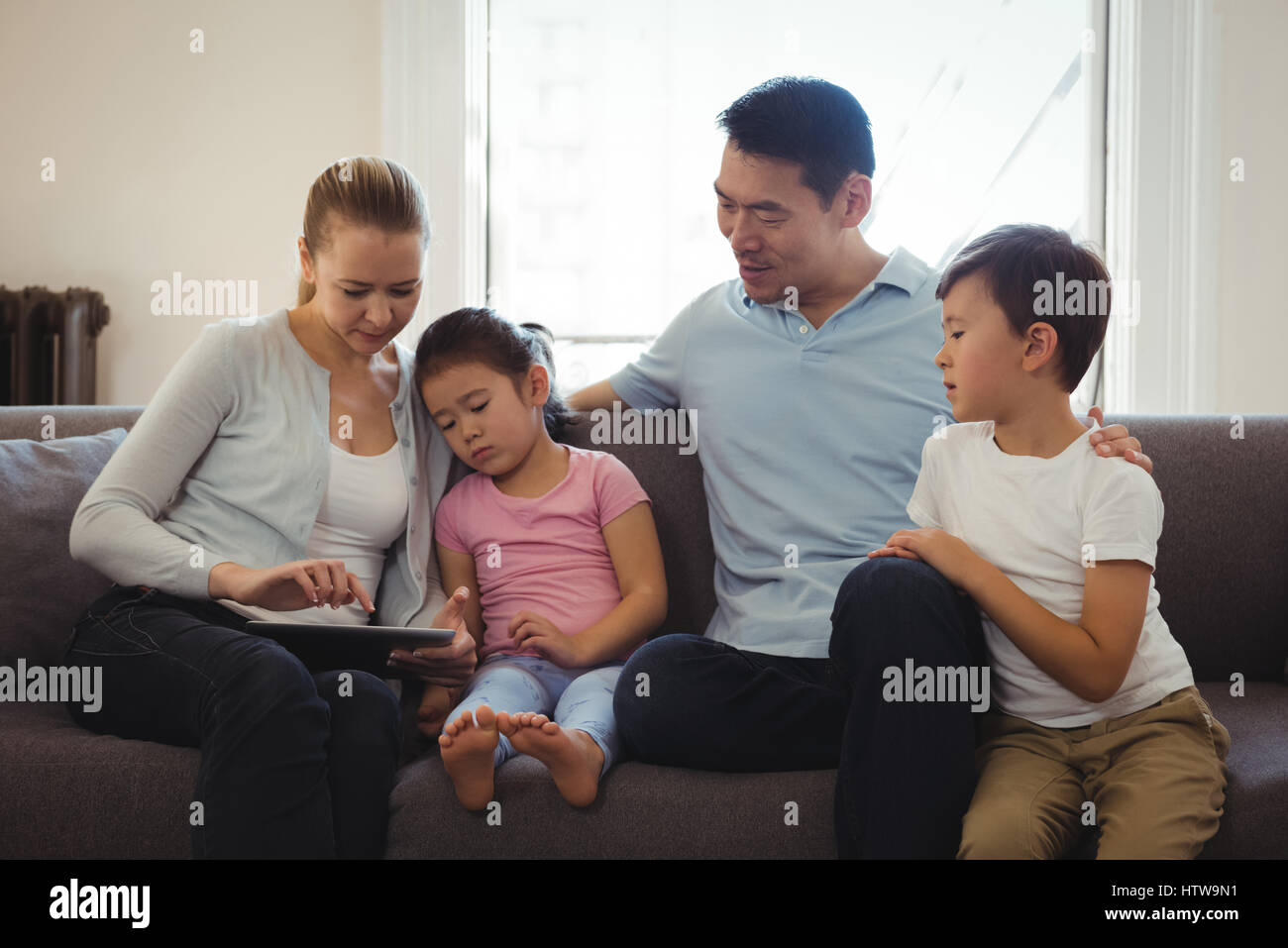 Parents et enfants using digital tablet in living room Banque D'Images