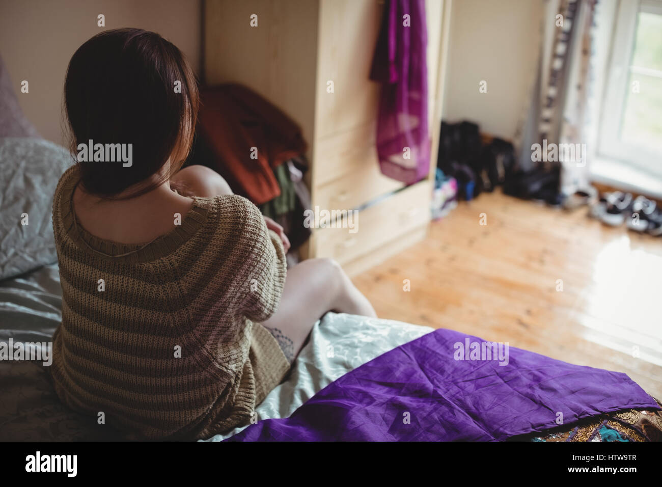 Femme assise sur le lit dans la chambre Banque D'Images