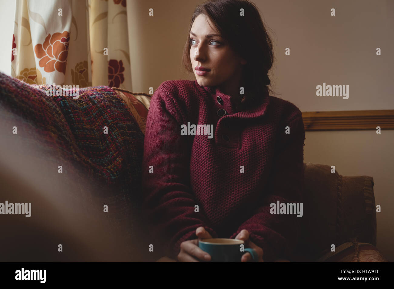 Une femme assise et tenant une tasse de café Banque D'Images