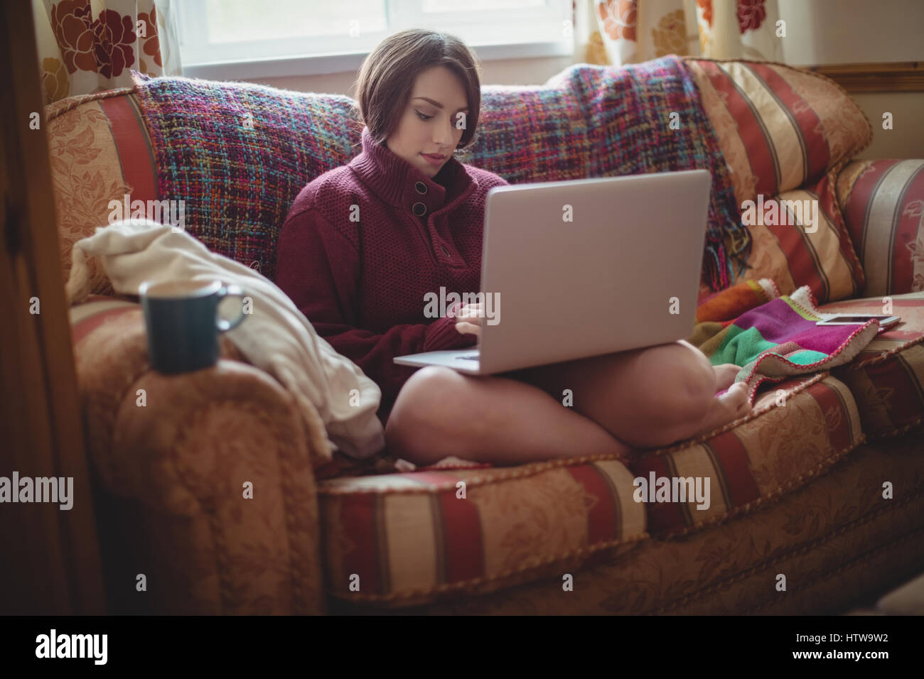 Beautiful woman on sofa and using laptop in living room Banque D'Images