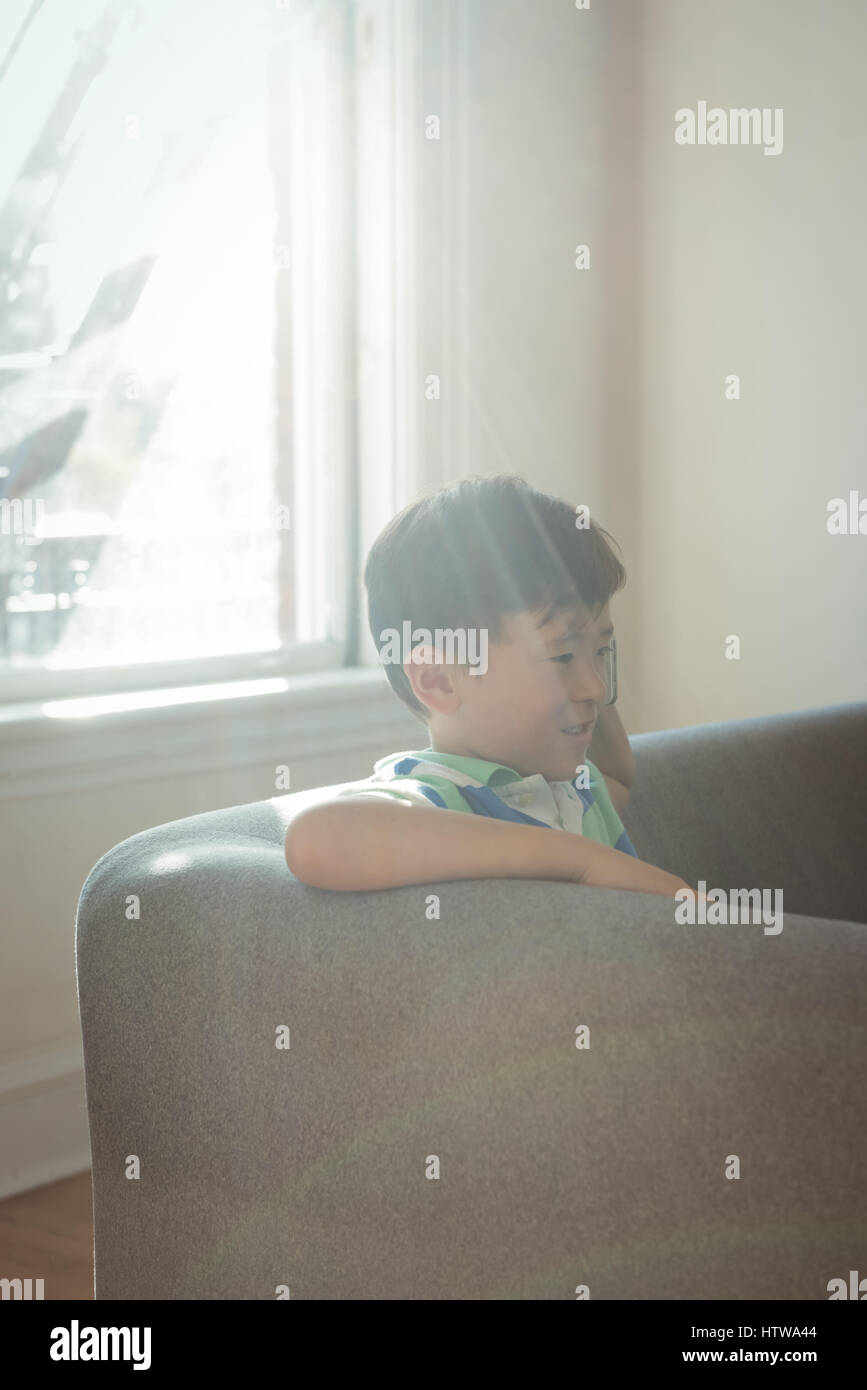 Boy sitting on sofa in living room Banque D'Images