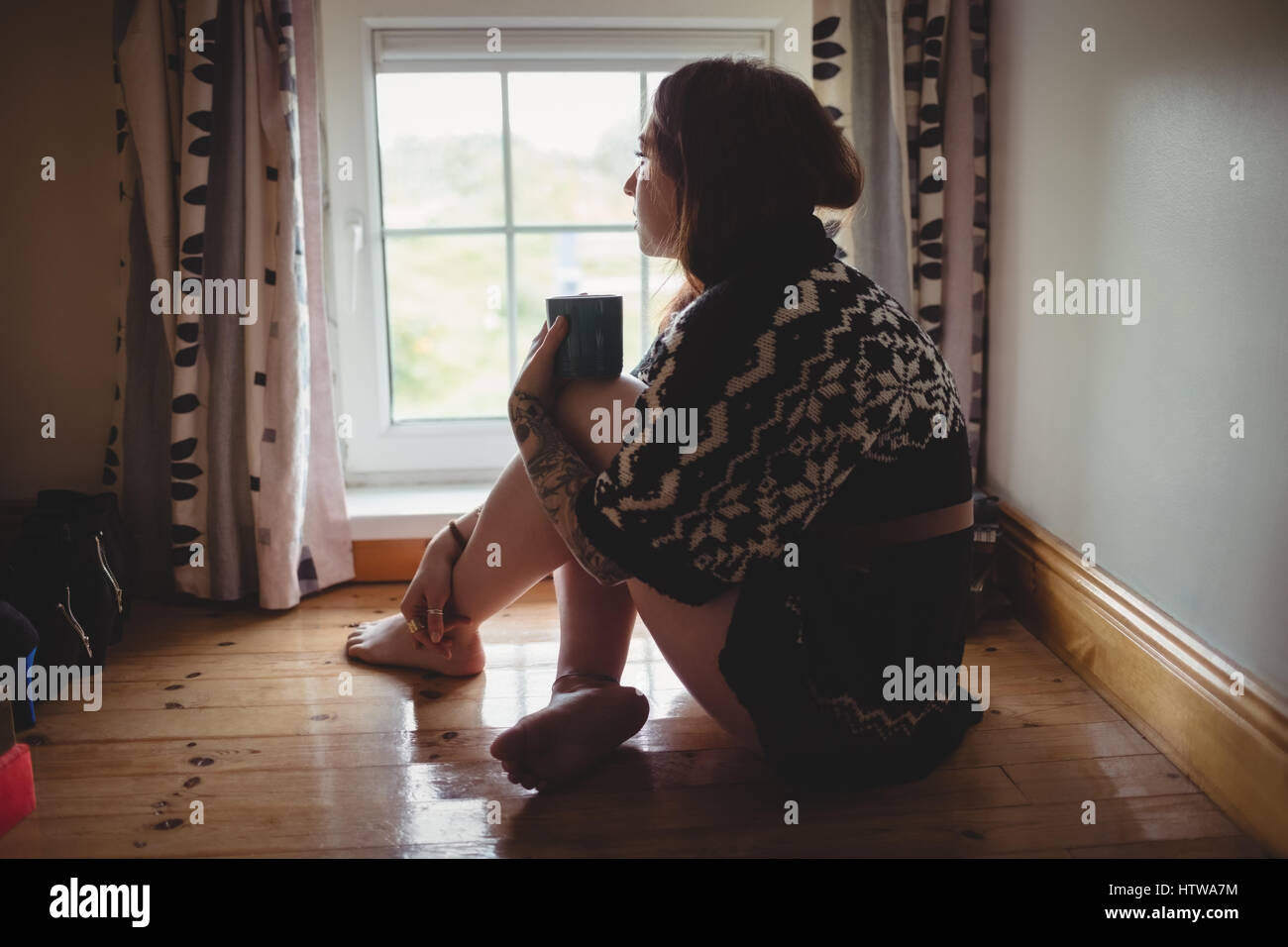 Thoughtful woman assis près de la fenêtre et le café Banque D'Images