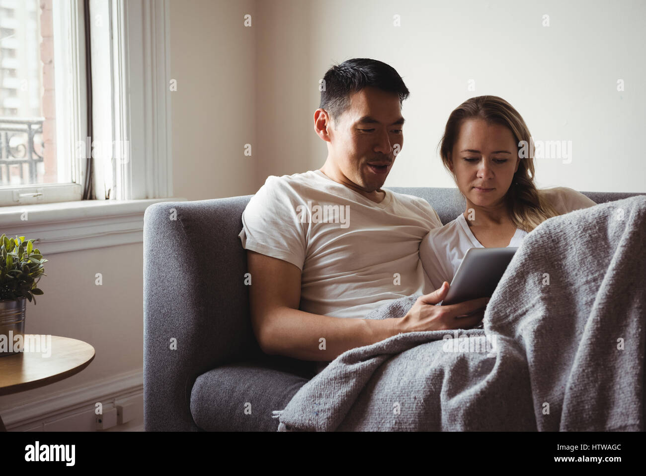 Couple using digital tablet in living room Banque D'Images