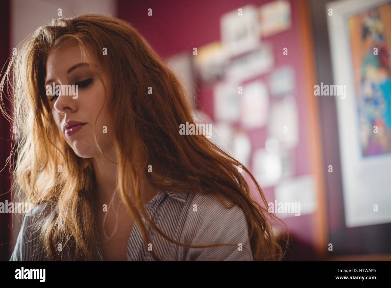 Thoughtful woman sitting in living room Banque D'Images