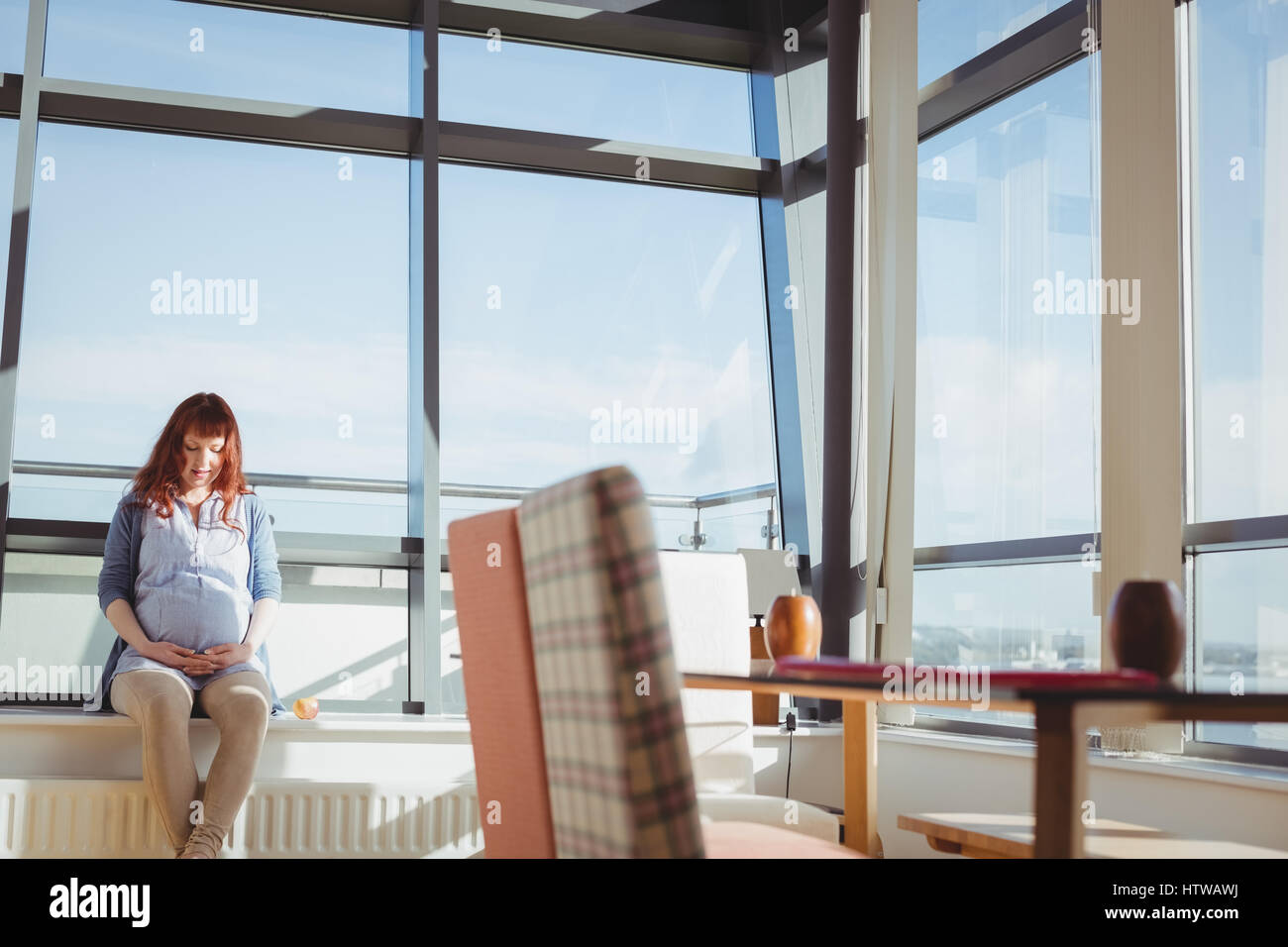 Une femme enceinte assis près de fenêtre dans salle de séjour Banque D'Images