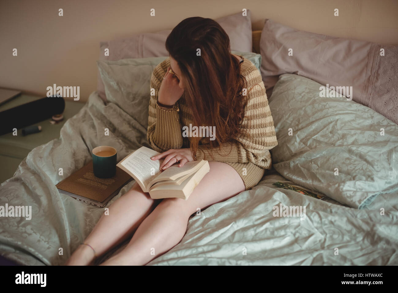 Femme assise sur le lit et la lecture d'un livre Banque D'Images