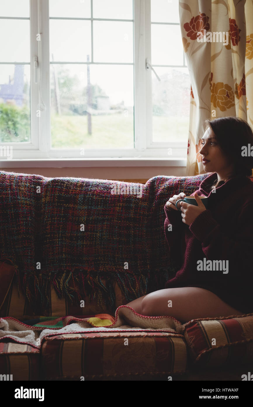 Une femme assise et tenant une tasse de café Banque D'Images