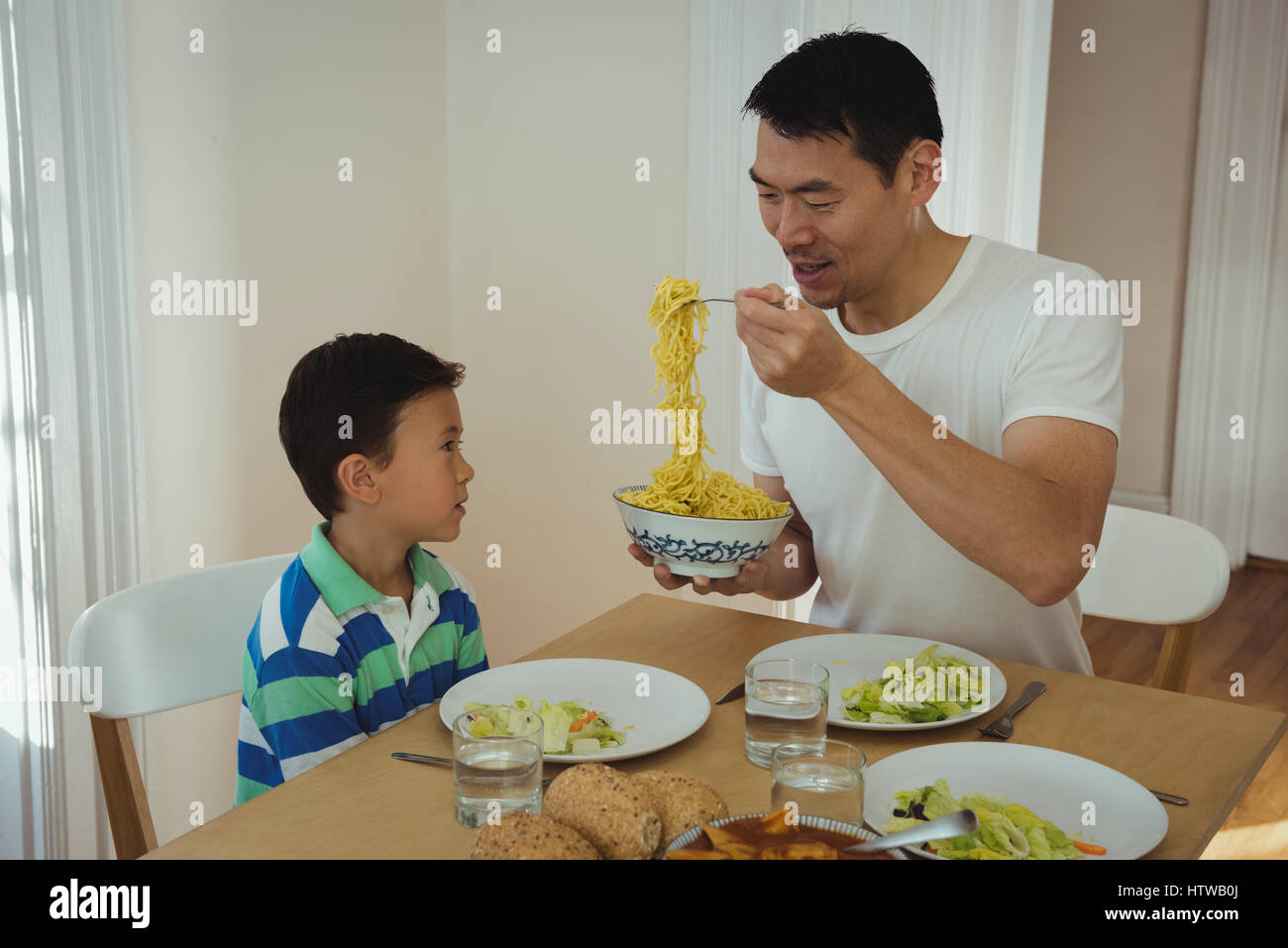 Père servant de la nourriture à son fils sur une table à manger Banque D'Images