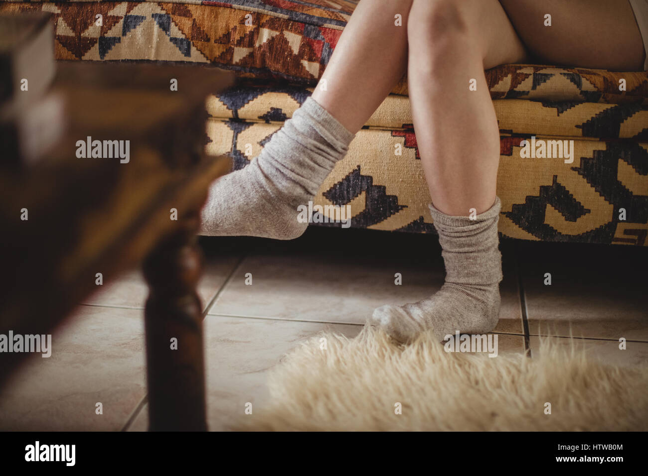 Chaussettes femme portant assis sur un canapé avec les jambes croisées Banque D'Images