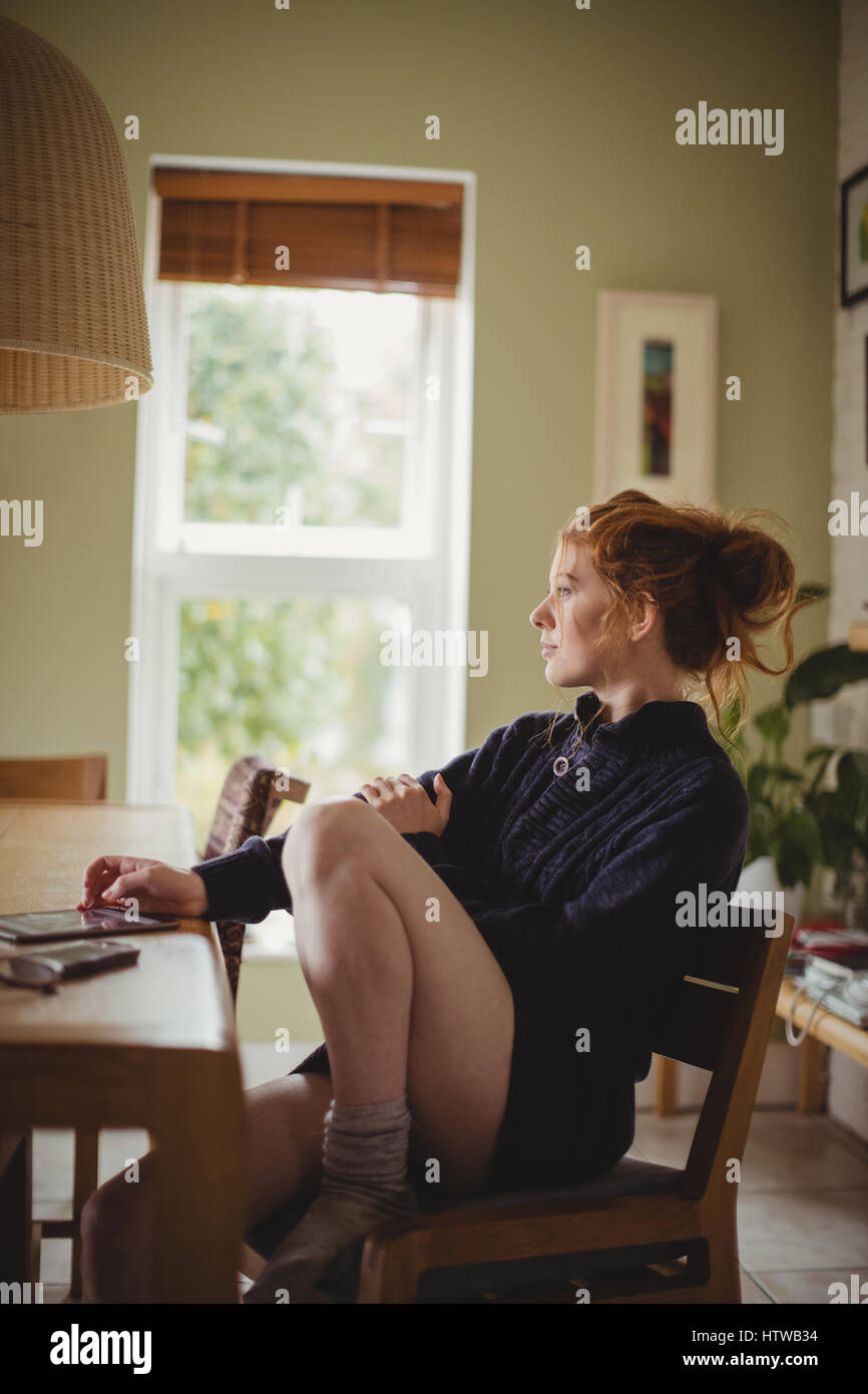 Thoughtful woman sitting at table à manger Banque D'Images