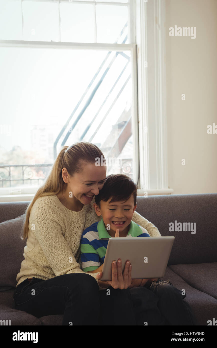 Mère et fils using digital tablet in living room Banque D'Images