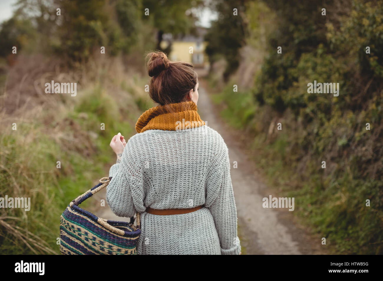 Femme avec panier de marcher sur la route entre les champs Banque D'Images