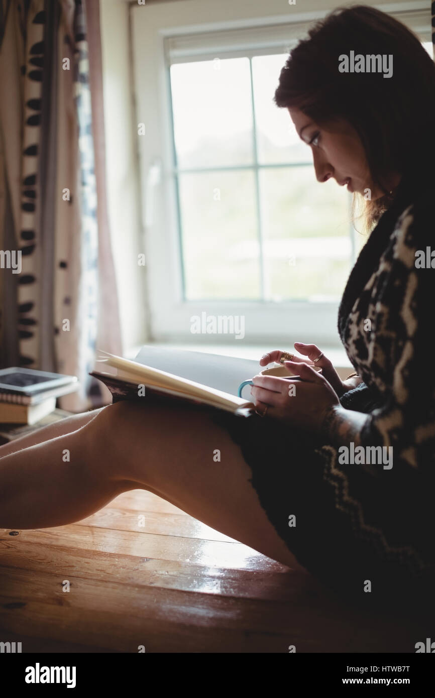 Femme assise près de la fenêtre et la lecture d'un livre Banque D'Images