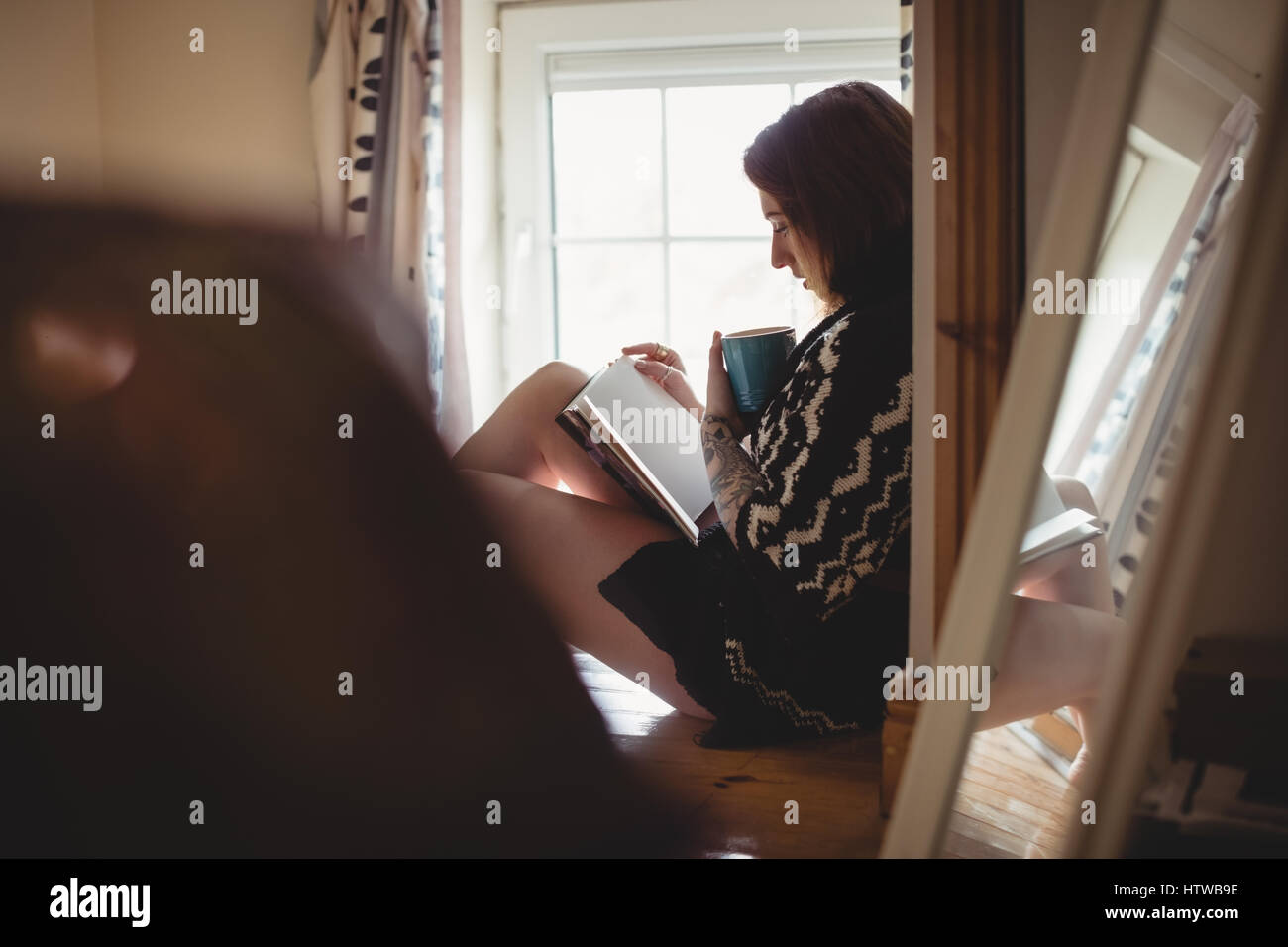 Femme assise près de la fenêtre et la lecture d'un livre Banque D'Images