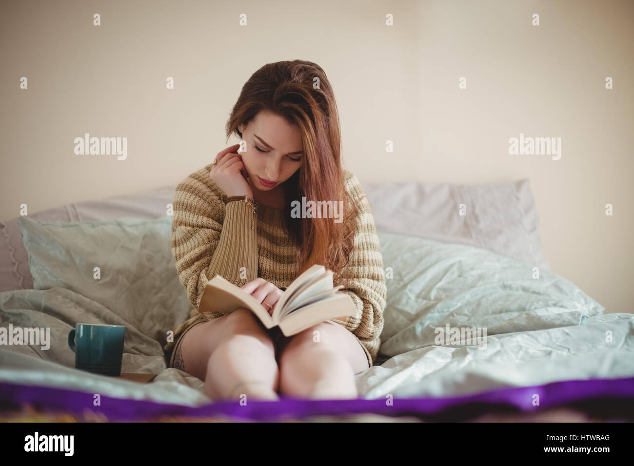Femme assise sur le lit et la lecture d'un livre Banque D'Images