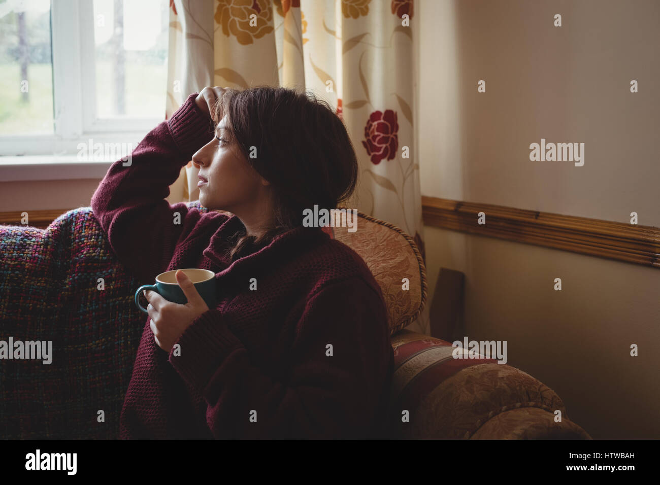 Une femme assise et tenant une tasse de café Banque D'Images