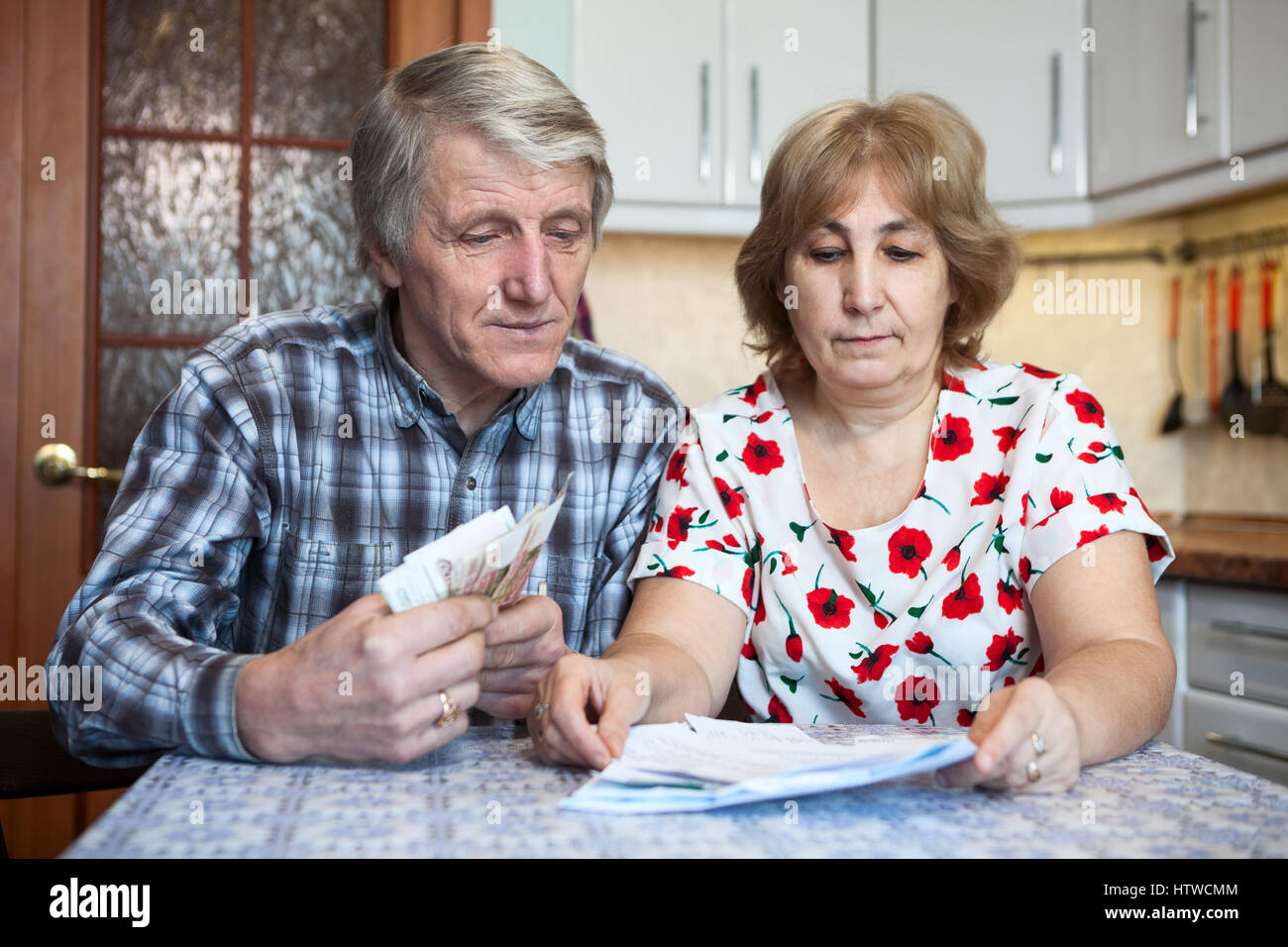 Couple de personnes âgées de race blanche de l'argent compte pour les paiements communautaires tout en étant assis à la table Banque D'Images