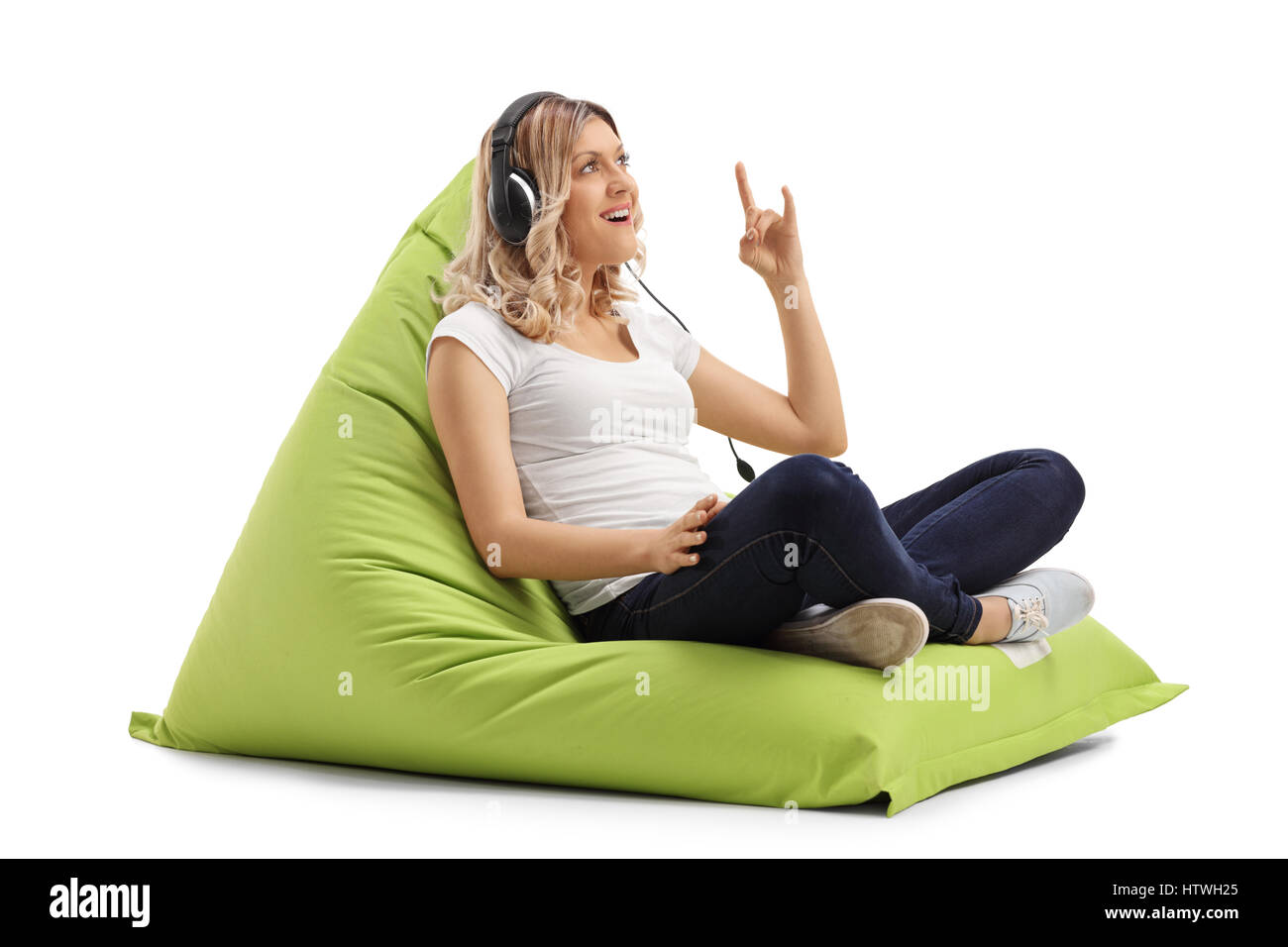 Jeune femme assise sur un pouf poire et écouter de la musique sur un casque  isolé sur fond blanc Photo Stock - Alamy