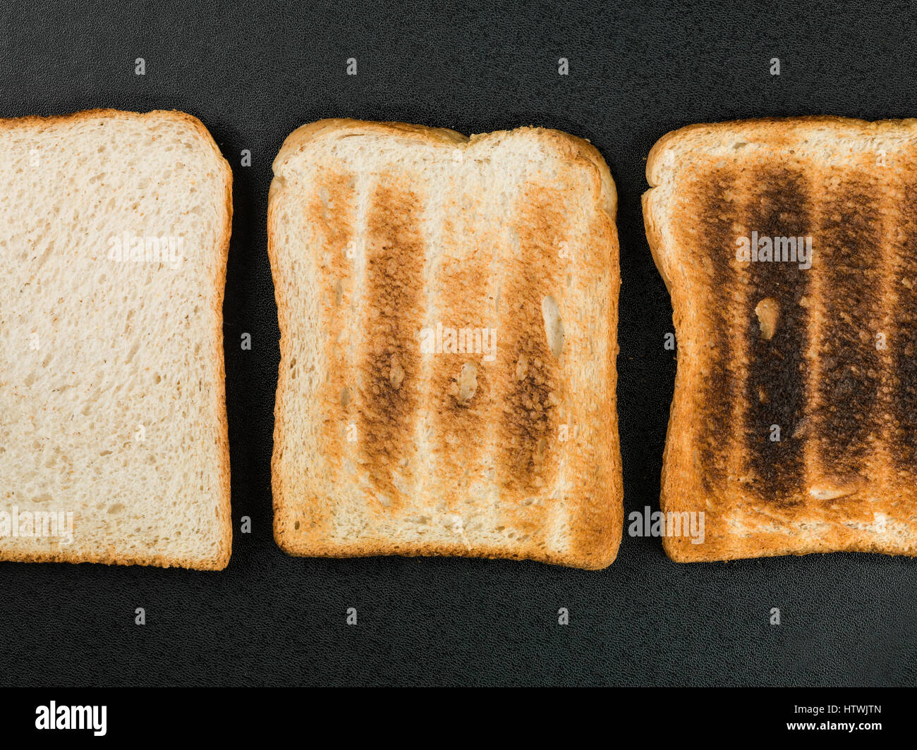 Tranches de pain grillé sur un fond noir de la viande trop cuite à Banque D'Images