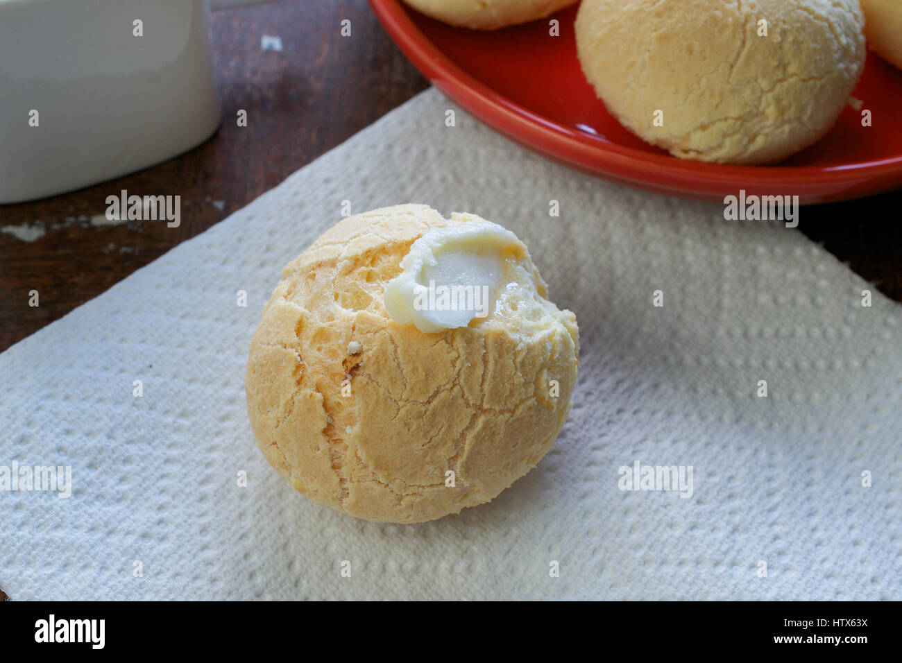 Gros plan sur la bouche-arrosage pain fromage brésilien (Pao de Queijo) garni de beurre à une serviette en papier blanc, et un groupe de pains dans l'arrière-plan sur Banque D'Images