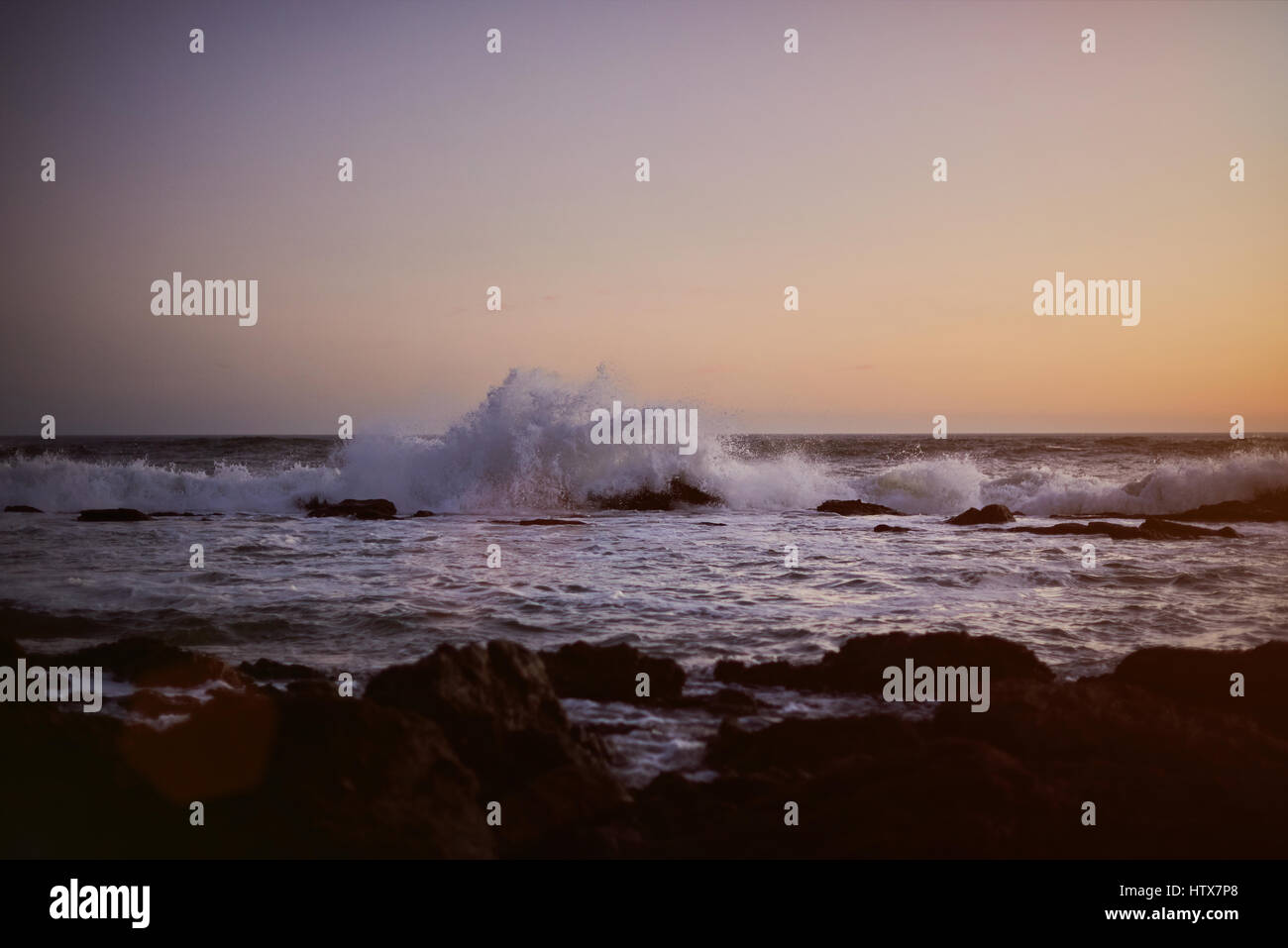 Océan vagues splash sur rock au coucher du soleil au crépuscule du temps. Vue panoramique sur la côte de l'océan au soleil d'or Banque D'Images