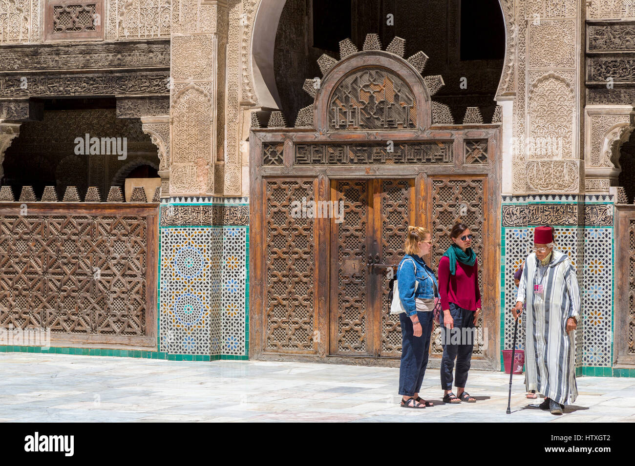 Fes, Maroc. Medersa Bou Inania. Les touristes avec guide dans la cour intérieure. Banque D'Images