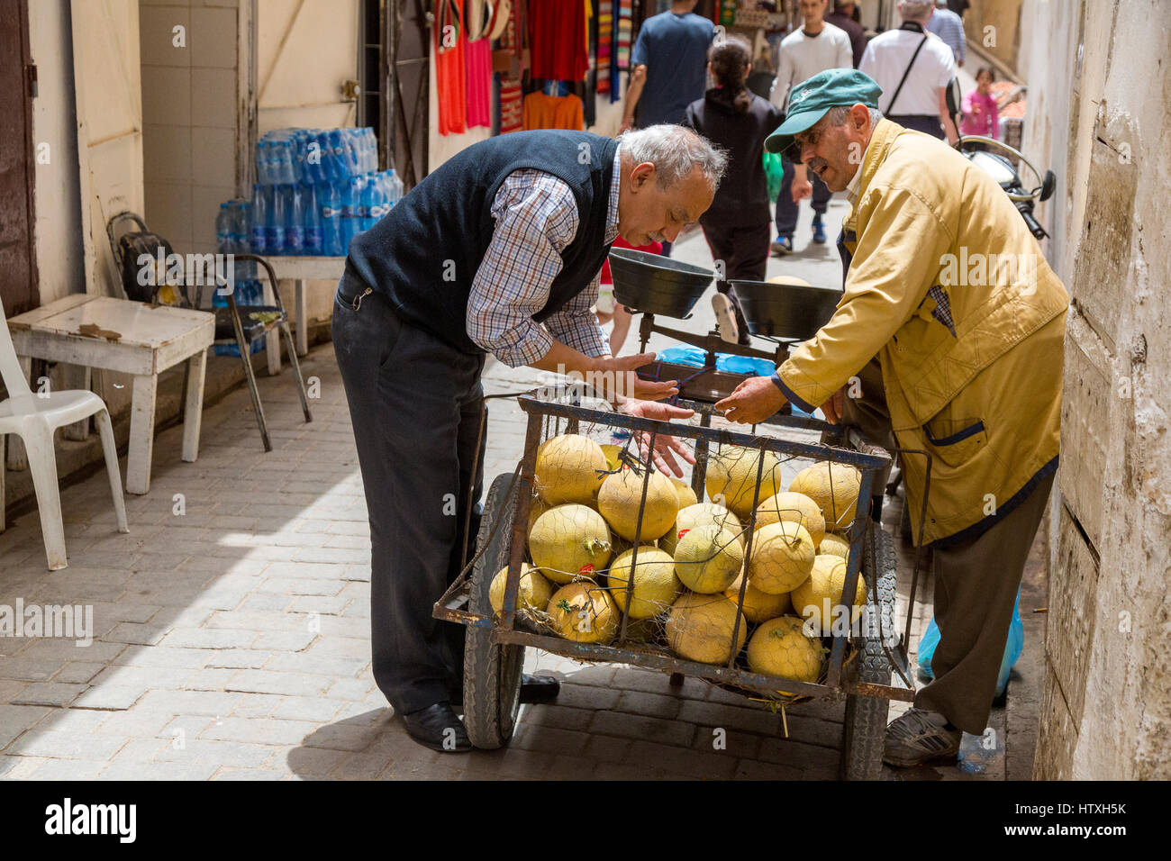 Fes, Maroc. Un vendeur de melons avec un client dans la médina. Banque D'Images