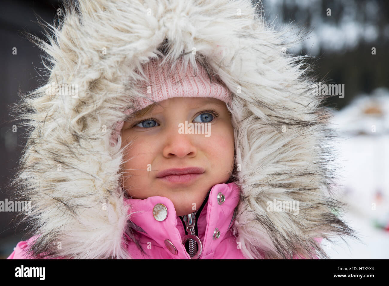 Portrait de petite fille habillée dans des vêtements d'hiver avec capuche à fourrure. Banque D'Images