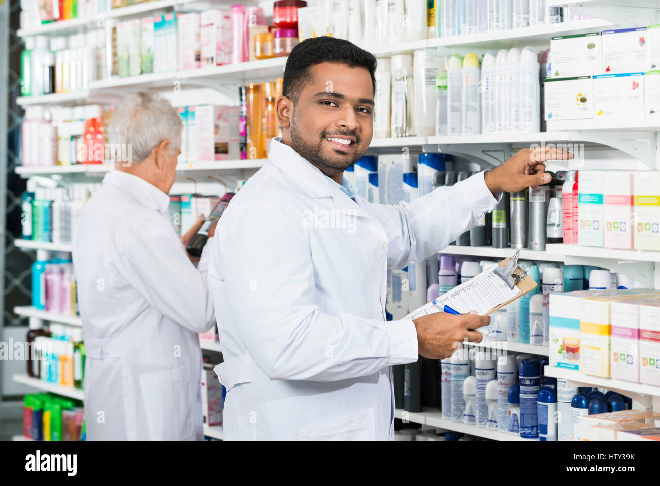 Smiling chemist stock comptage avec collègue en pharmacie Banque D'Images