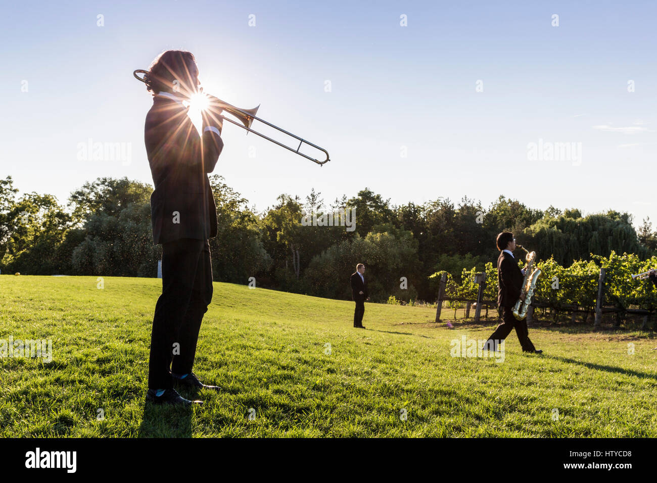 Musicien jouant un trombone à l'extérieur contre un ciel bleu et soleil éclaté Banque D'Images