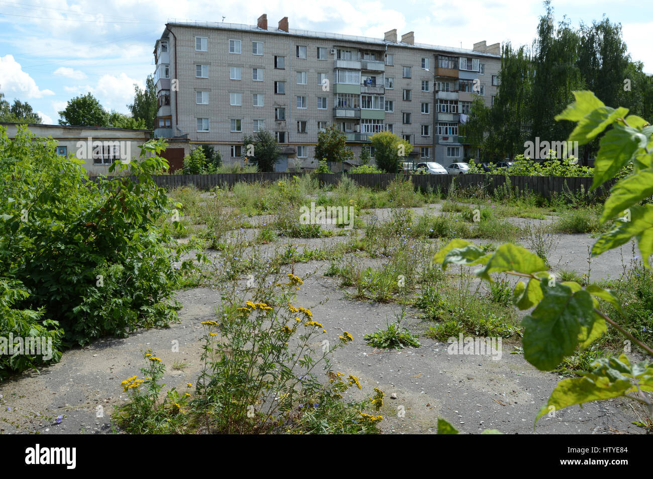 KOVROV, Russie - le 30 juillet 2015 : envahis par les herbes et les buissons aire de hockey dans la cour d'un immeuble de plusieurs étages Banque D'Images