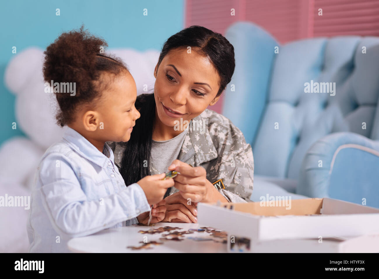 Genre attentionné maman donnant son enfant un morceau de puzzle Banque D'Images