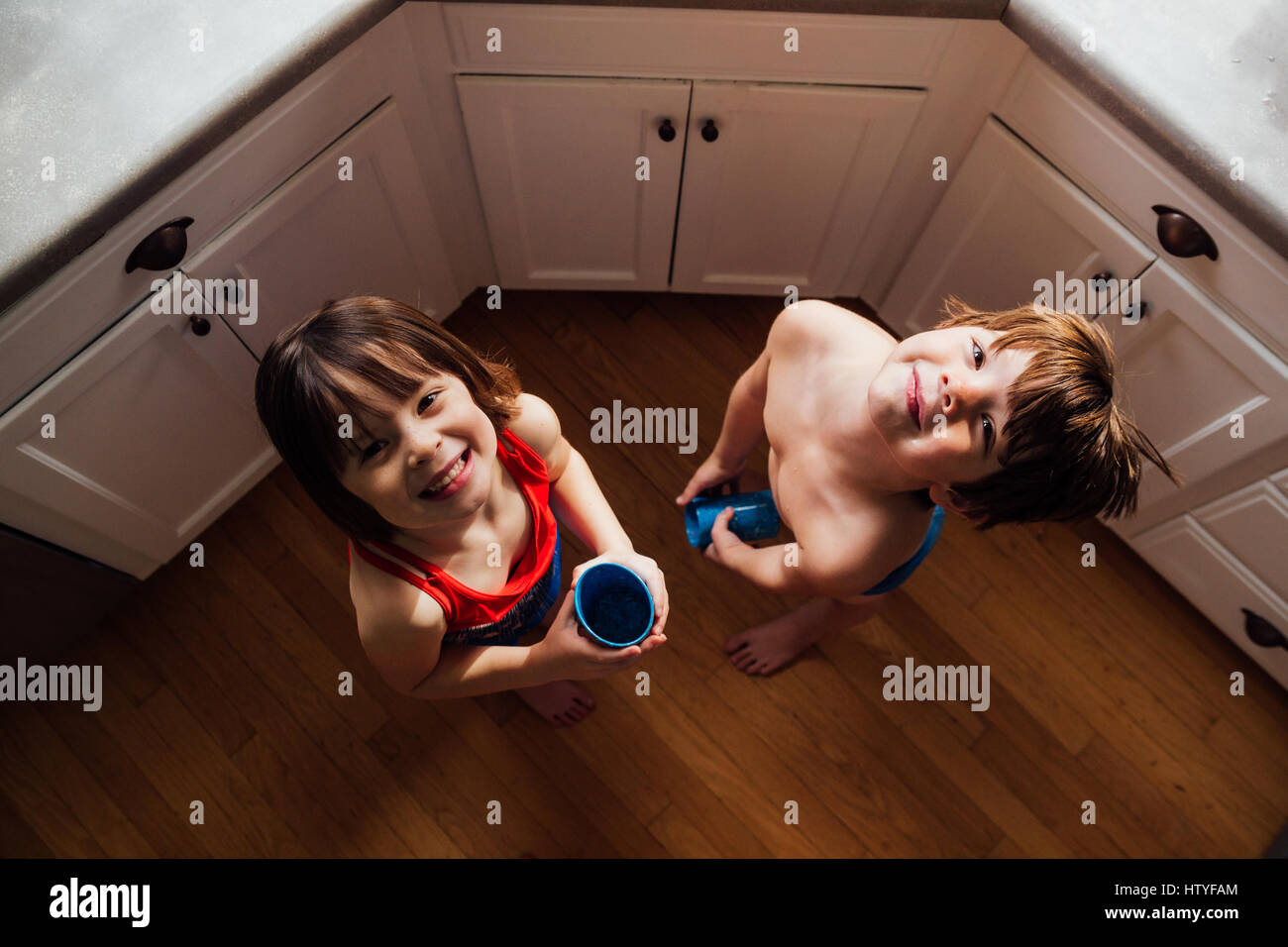 Garçon et fille debout dans l'eau potable de cuisine Banque D'Images