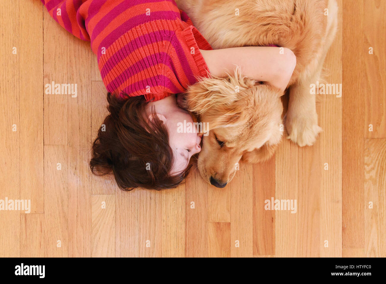 Girl lying on floor serrant un golden retriever dog Banque D'Images