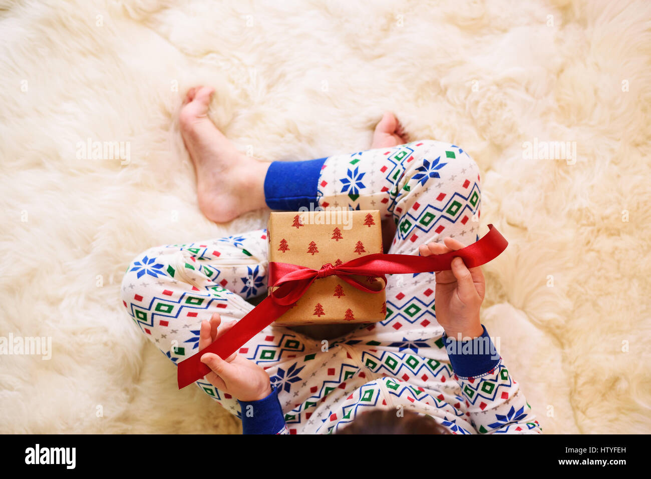 Girl's assis sur le plancher de l'ouverture d'un cadeau de Noël Banque D'Images