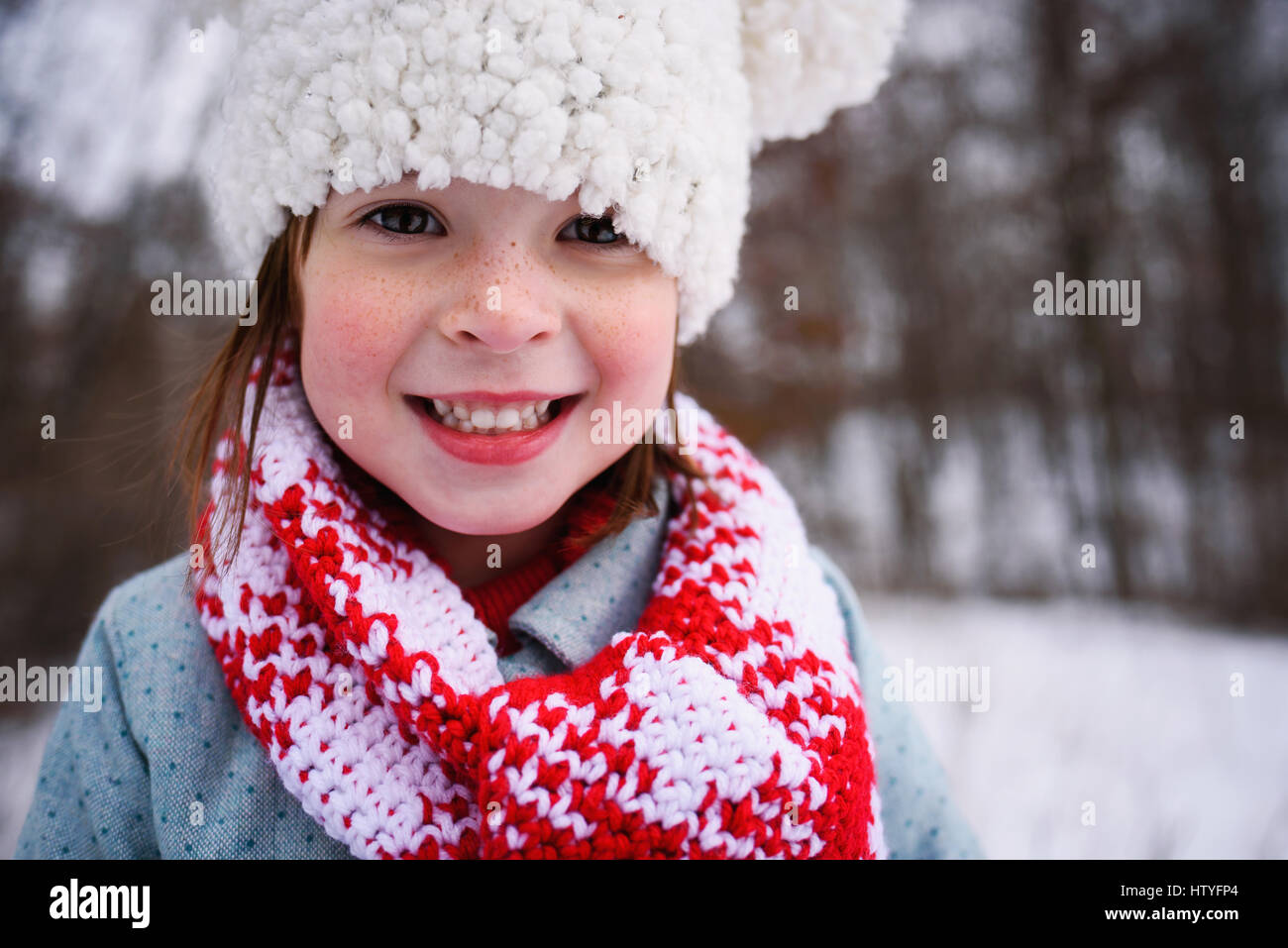 Portrait of a smiling girl in a bobble hat dans la neige Banque D'Images