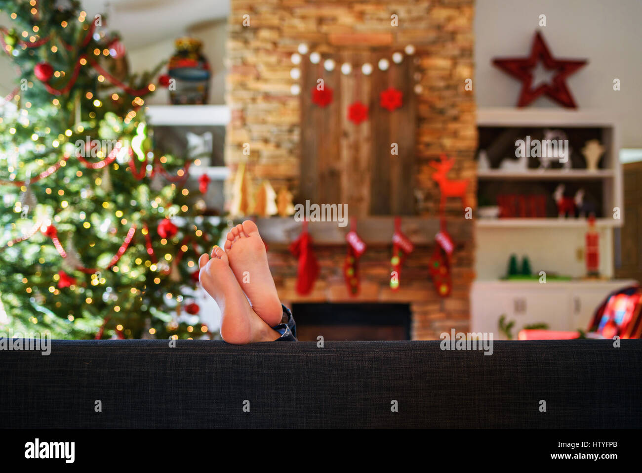 Les pieds de la jeune fille sur un canapé dans la salle de séjour à Noël Banque D'Images
