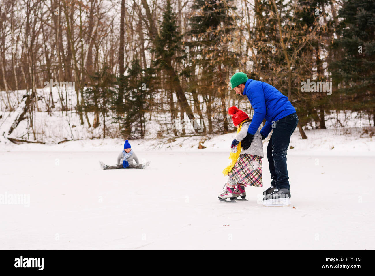 Père et deux enfants du patin à glace sur un lac Banque D'Images