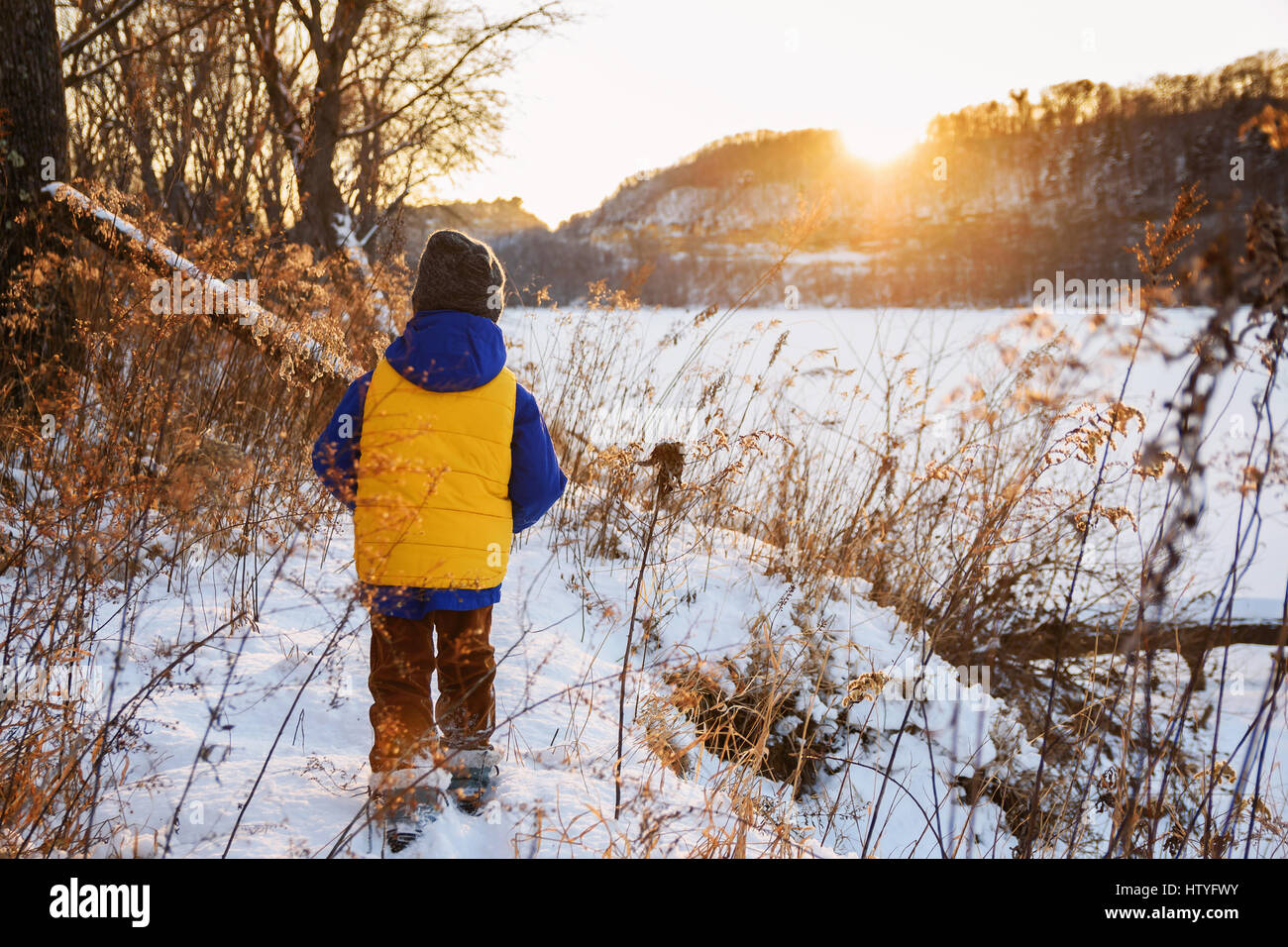 Garçon marchant le long d'une rivière dans la neige Banque D'Images