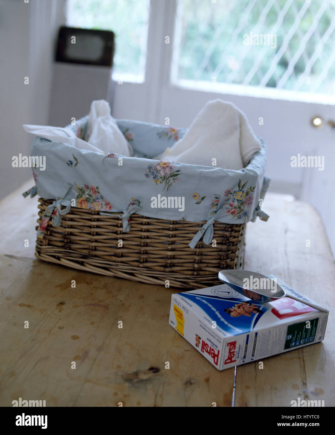 Paquet de lessive en poudre Persil sur table avec panier à linge doublé coton floral Banque D'Images