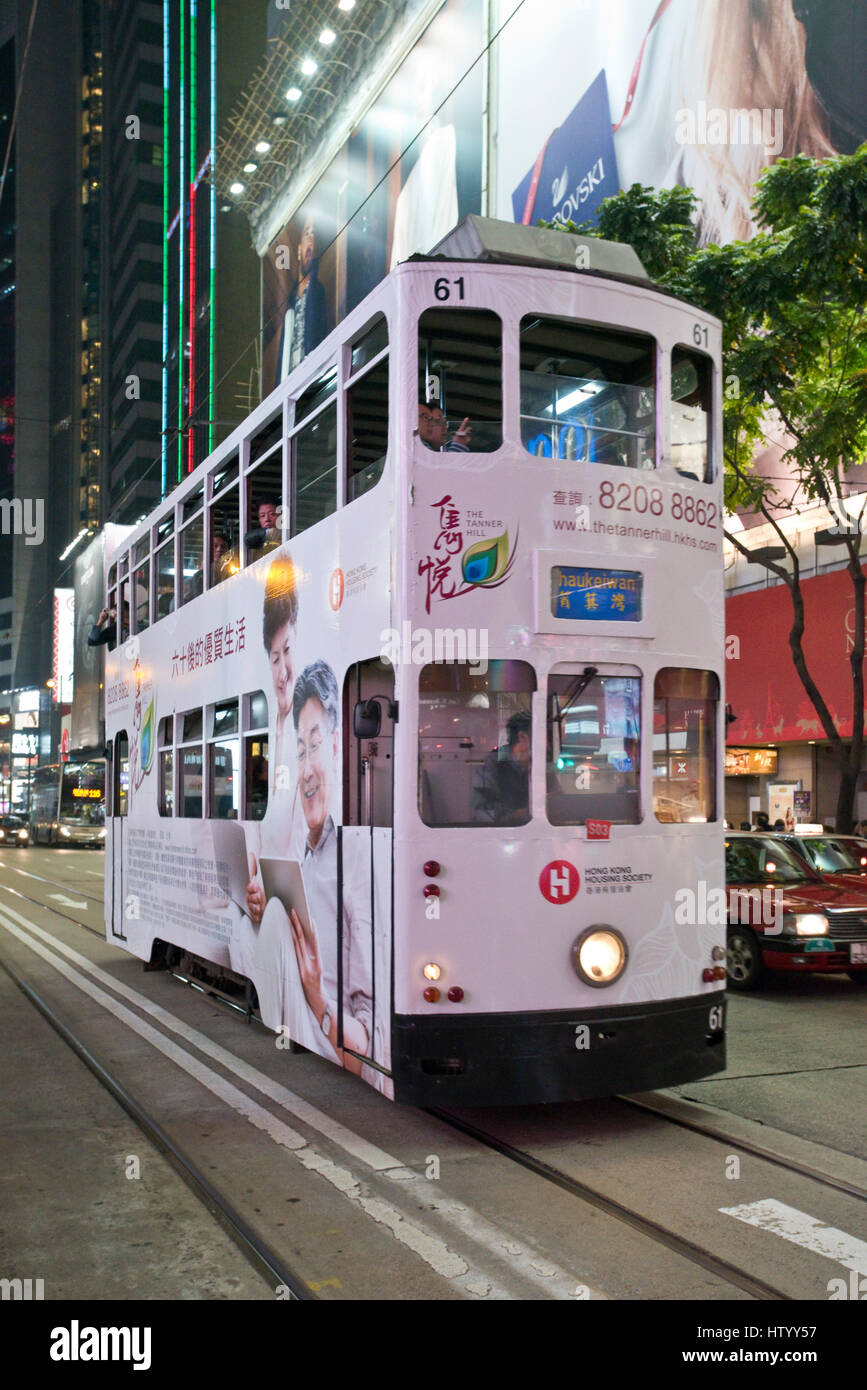 Un tram traverser une intersection achalandée des piétons traversant la rue avec des néons à Causeway Bay, Hong Kong Island, avec un effet de flou. Banque D'Images