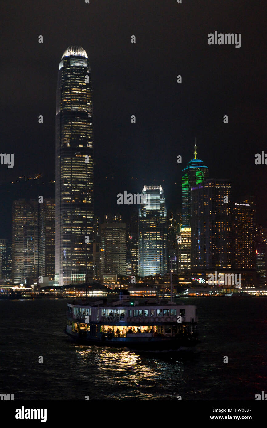 Un paysage urbain voir des bâtiments le long de l'île de Hong Kong avec une Star Ferry dans l'avant-plan dans la nuit. Banque D'Images