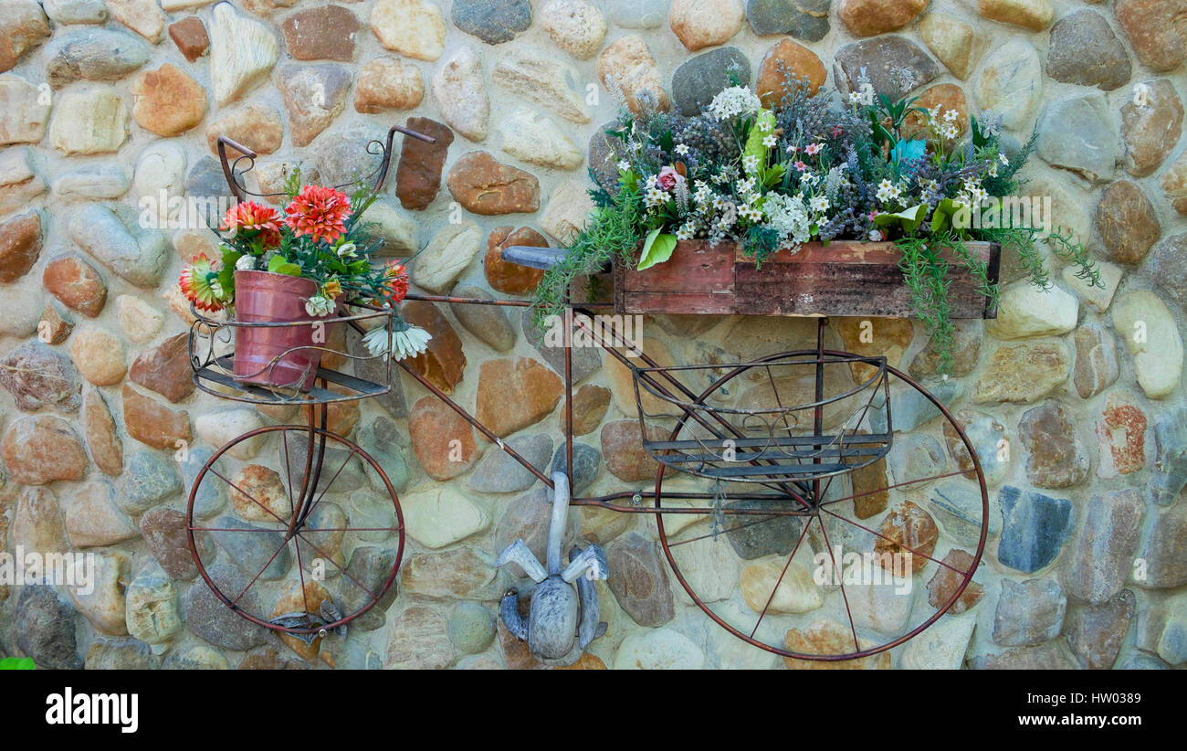 La vieille bicyclette sur mur en pierre, fleurs panier sur la location Banque D'Images