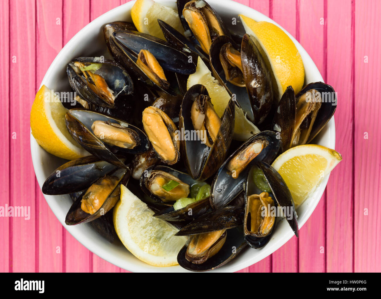 Les moules cultivées de corde dans une sauce à l'ail et l'échalote avec des tranches de citron Banque D'Images