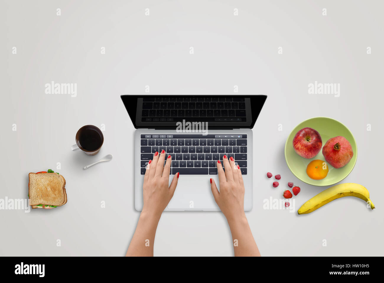 Femme travail sur ordinateur portable. Fruits frais et un sandwich à côté. L'alimentation saine sur office 24. Écran noir pour une maquette. Banque D'Images