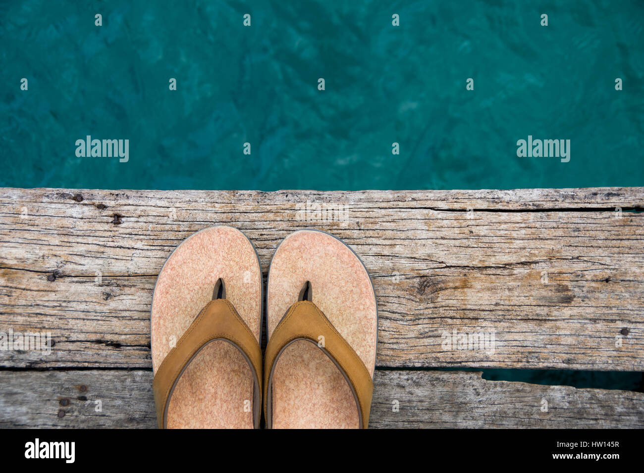 Sandales Beige volte-face sur le bord du quai en bois au-dessus de l'eau Banque D'Images