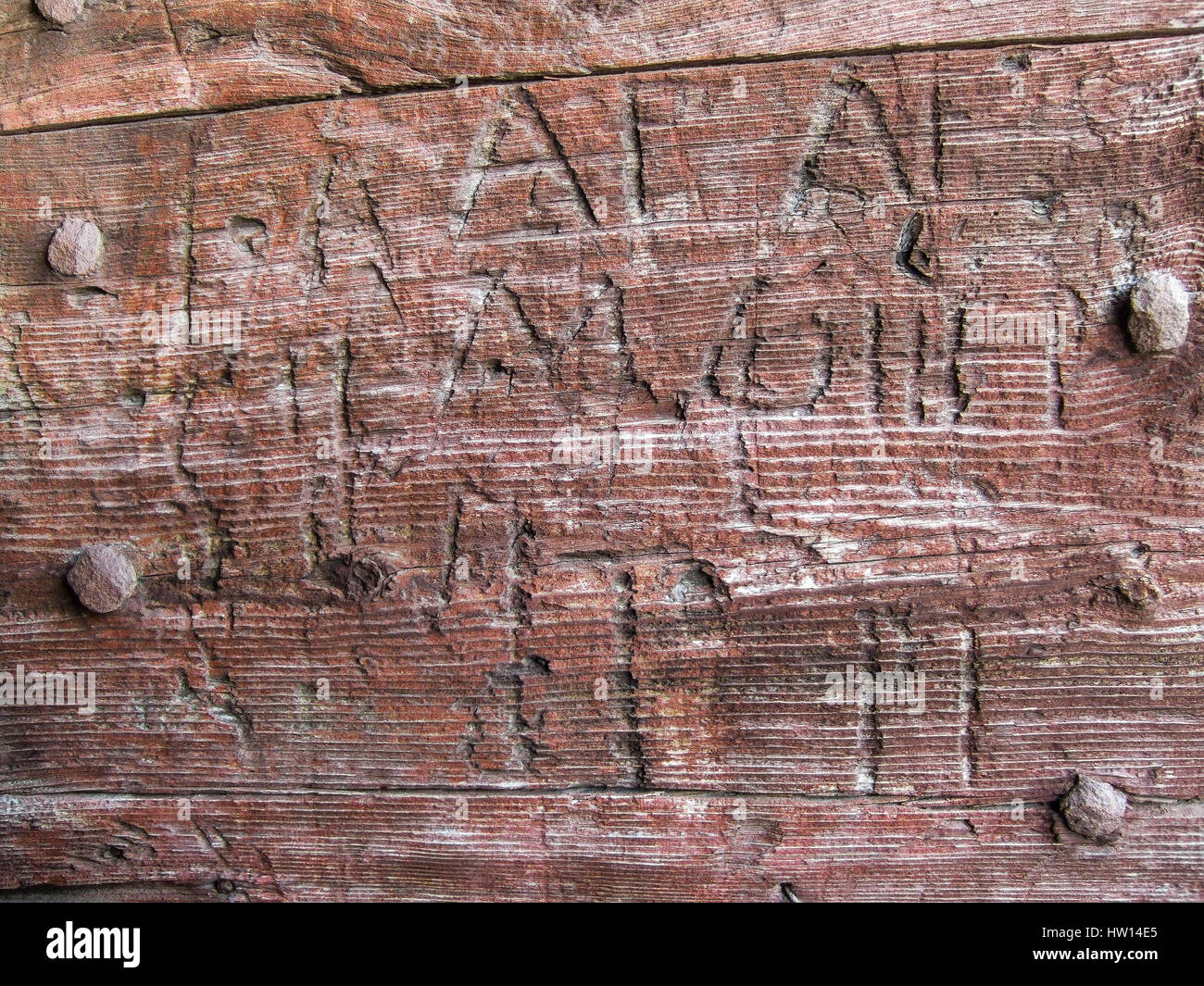 L'inscription de graffitis sur la porte en bois. Mots creusé dans une chapelle en bois avec porte d'ornements métalliques rouillées (France) Banque D'Images