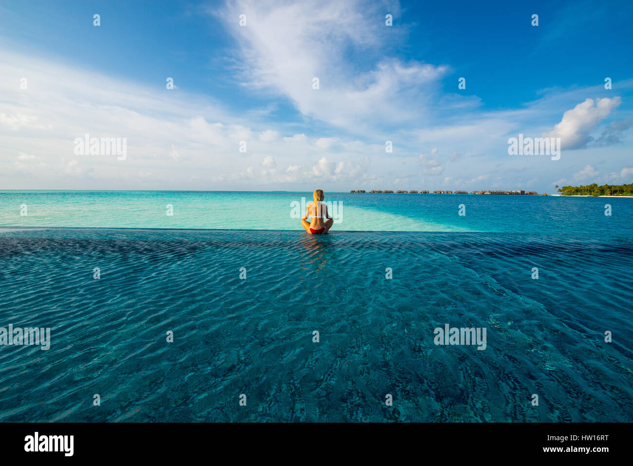 Les Maldives, Rangali Island. Conrad Hilton Resort. Femme dans une piscine à débordement sur l'océan. (MR) Banque D'Images