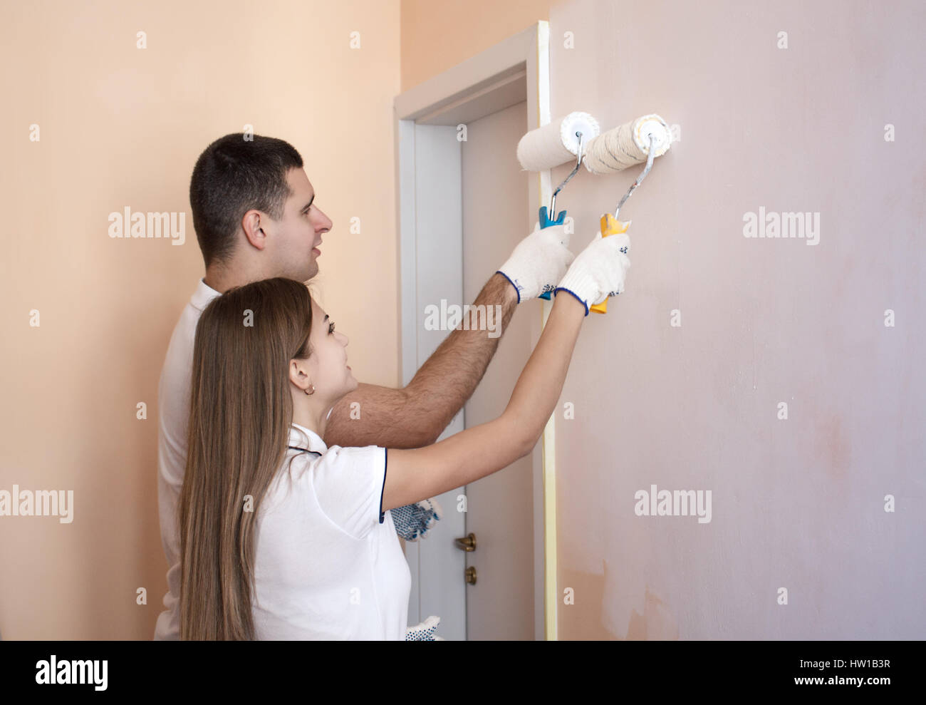 Portrait of happy young couple painting mur intérieur de maison ou appartement. Ils sont maintenant rouleau pour la peinture. Banque D'Images